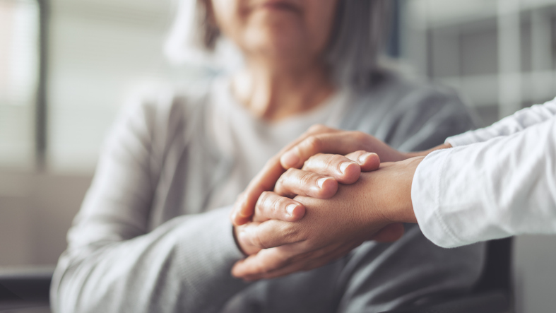 Young woman holding her elderly mother's hand