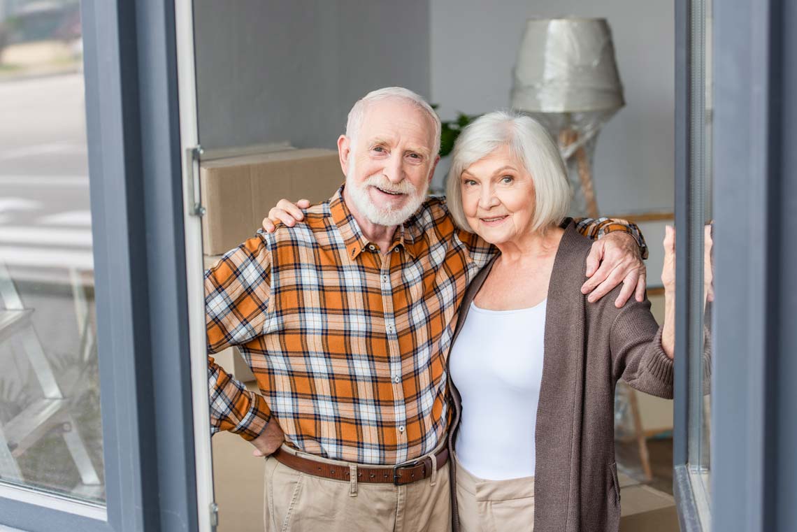 Happy senior couple smiling after packing home to relocated to assisted living community