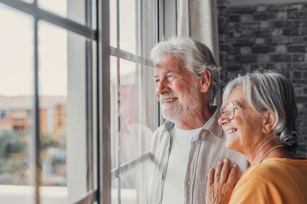 Happy senior couple enjoying each other’s presence, gazing out of the window