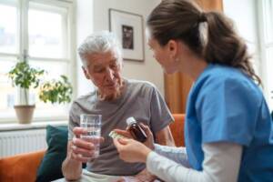 Older male Chelsea resident getting help with medication management from an on-site nurse