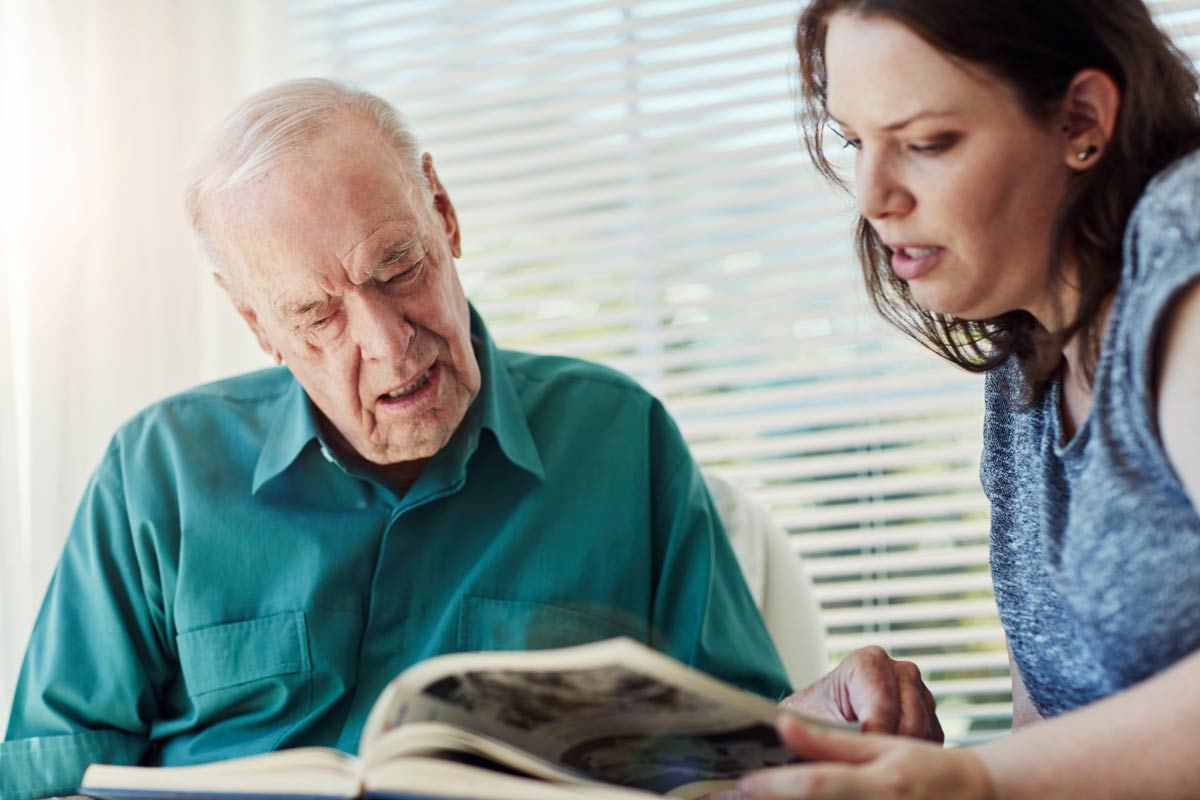 Elderly father, daughter and looking at photo album with retirement, memory nostalgia and remember in home