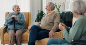 Happy seniors enjoying a conversation in the living room of an assisted living apartment
