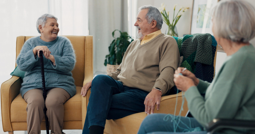 Happy seniors enjoying a conversation in the living room of an assisted living apartment