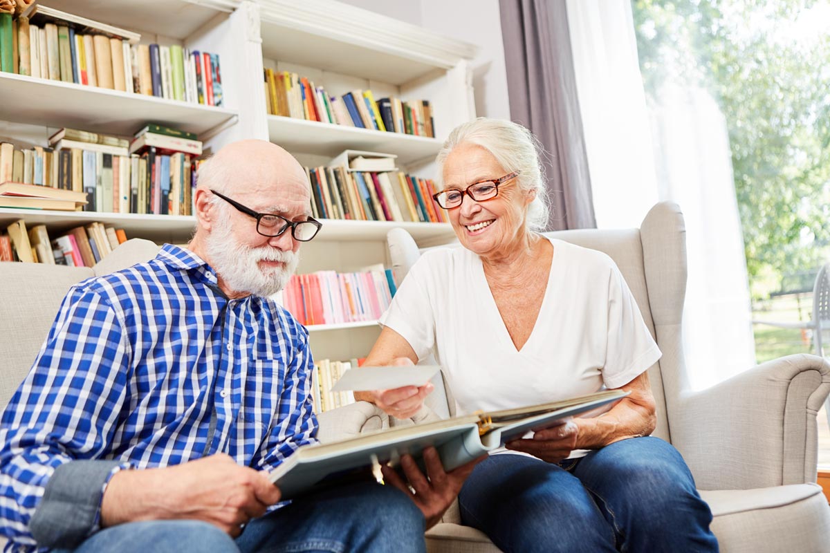 Couple of retired seniors together looking at photos in the senior citizen apartment