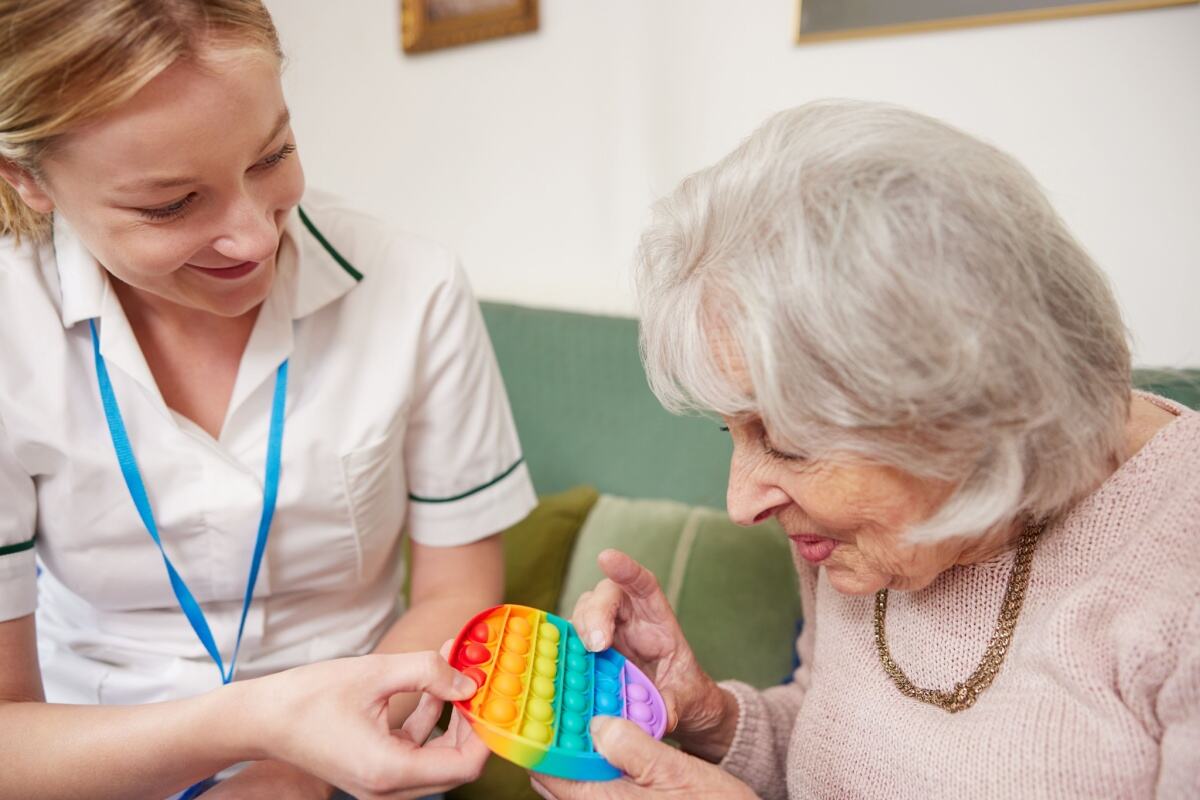 Female Physiotherapist Getting Senior Woman to Use Fidget Toy.