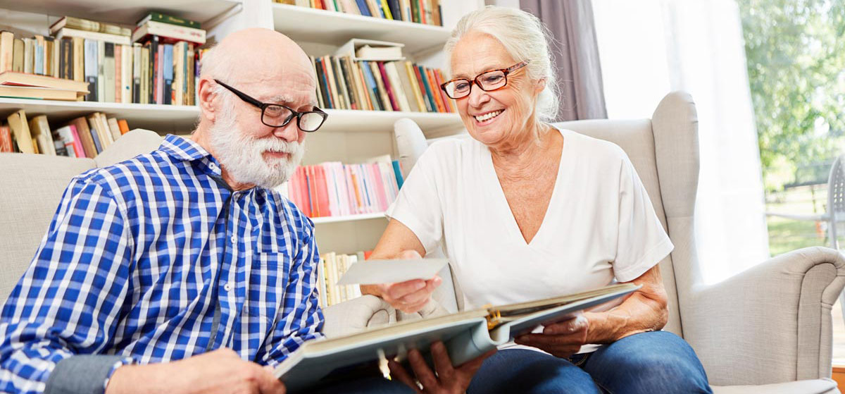 Couple of retired seniors together looking at photos in the senior citizen apartment